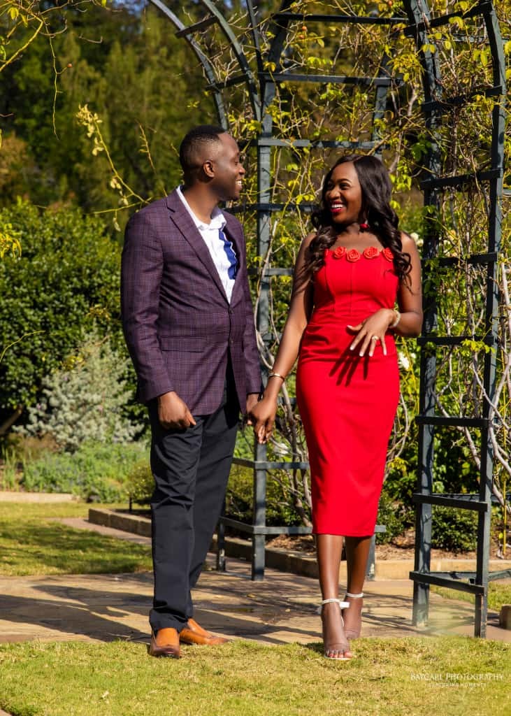 Tolu and Dami walking hand in hand through a garden arbor